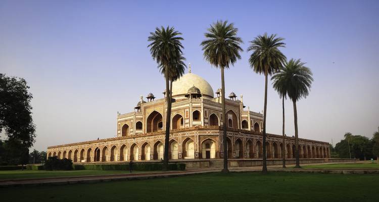 View of a historic mausoleum with a lawn and trees.