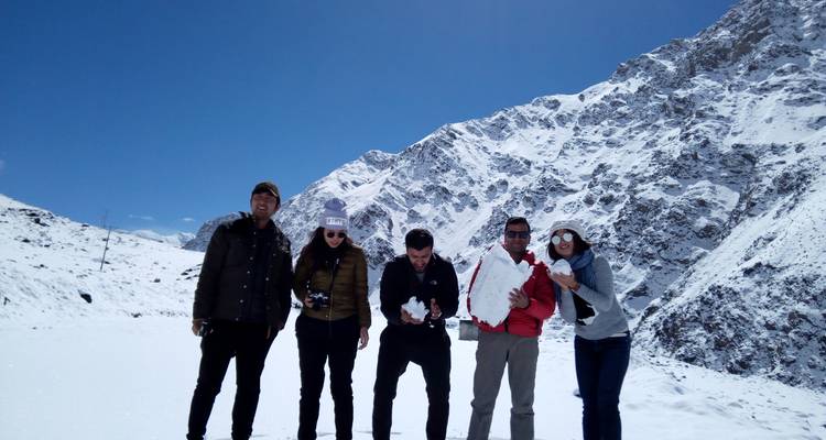 Cinq personnes jouant avec la neige devant des montagnes enneigées.