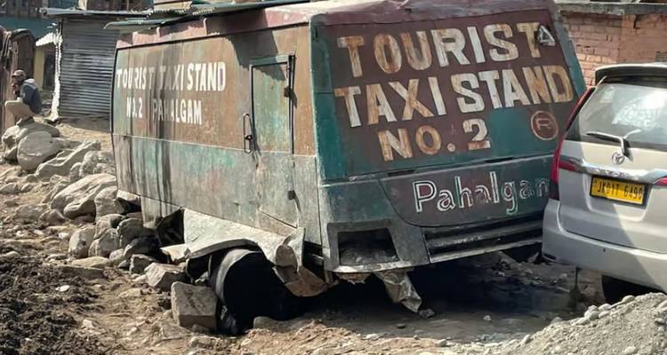Roestend kapot buslichaam gemarkeerd 'Tourist Taxi Stand Pahalgam' verlaten naast rotsachtige weg.