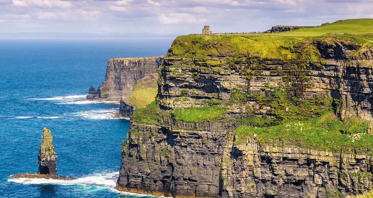 Dramáticos acantilados de Moher vestidos de verde que se precipitan al Océano Atlántico con farallones marinos abajo.