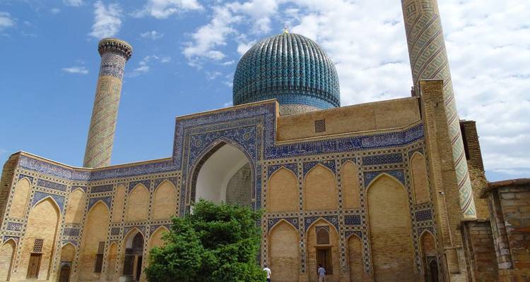 Blau-kuppeliges Mausoleum umrahmt von verziertem Backstein und Fliesenwerk mit Minaretten
