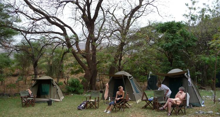 People sitting outside tents in a camping area.