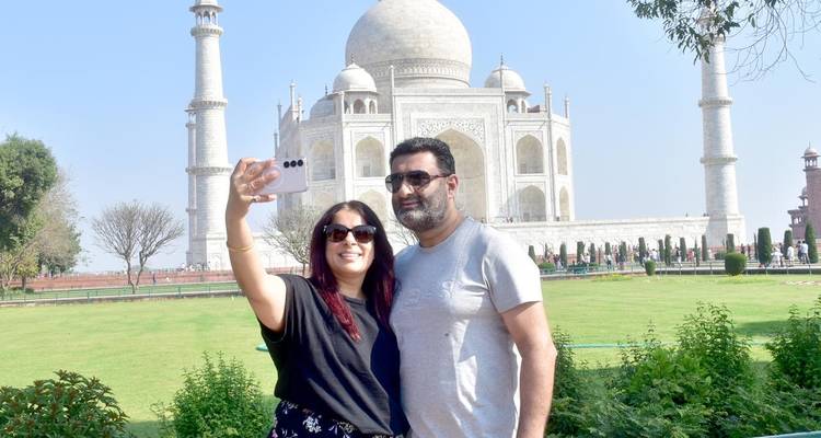 Stel dat een selfie maakt met het iconische witte marmeren Taj Mahal dat achter hen omhoog rijst op een zonnige dag.