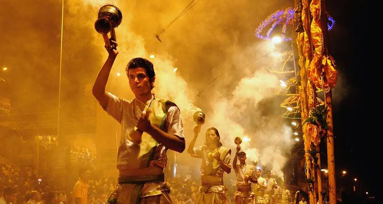 Personas realizando una ceremonia tradicional con humo y luces por la noche.