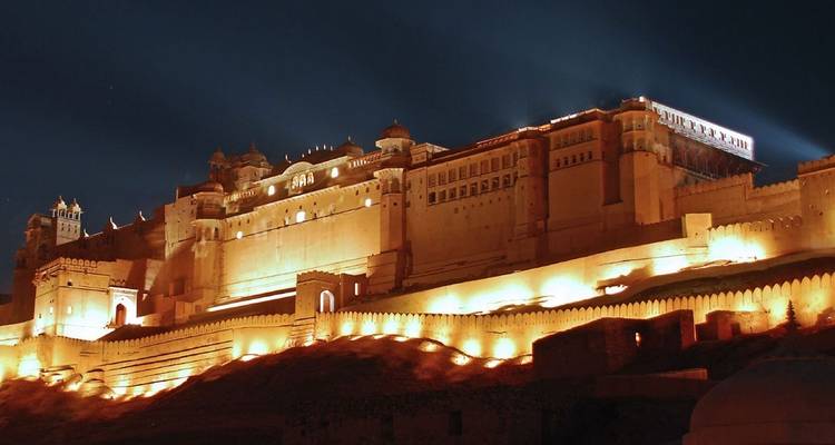 Fortaleza iluminada en una colina por la noche bajo un cielo estrellado.
