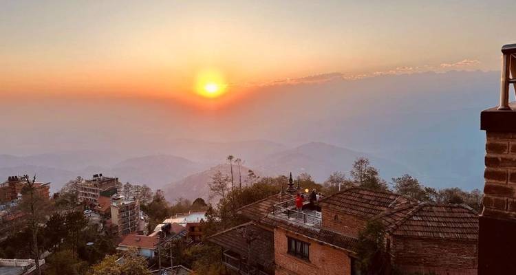 Gouden zonsopgang boven mistige Himalayavoorheuvels en rustieke bakstenen daken.
