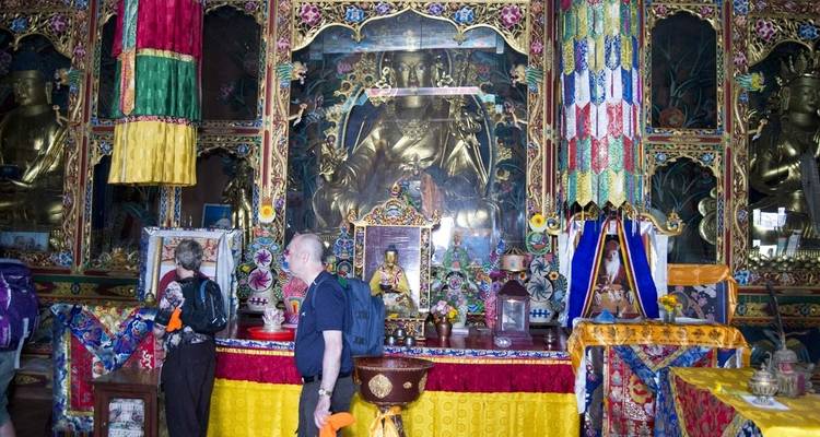 Des touristes à l'intérieur d'un temple coloré avec des statues ornées.