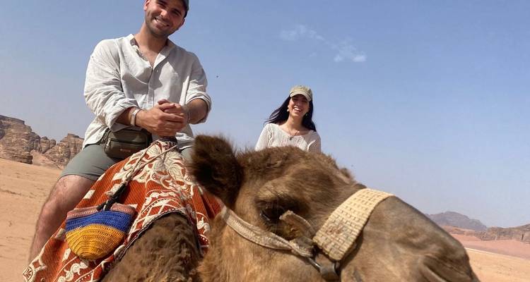 Una pareja montando un camello en un desierto.