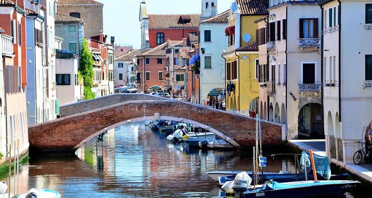 Scène pittoresque de canal avec un pont de pierre et des bateaux.