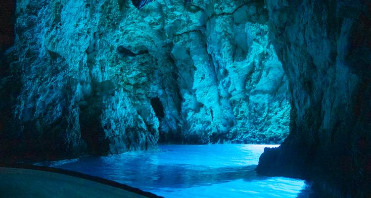 Intérieur mystique éclairé de bleu de la grotte marine aux parois calcaires dentelées et aux eaux cristallines