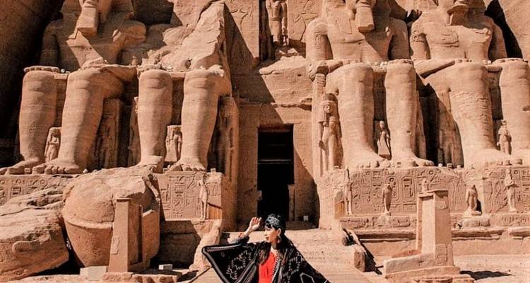 Een vrouw staat voor de massieve standbeelden van Abu Simbel.