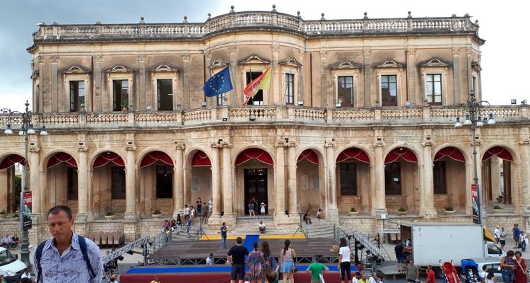 Historisches Gebäude mit Flaggen und Menschen, die sich davor versammeln.