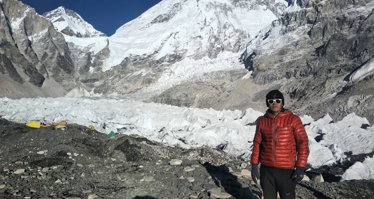 Persoon in buitenkleding staand in besneeuwd bergachtig gebied.