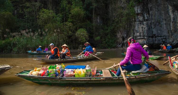 Plaatselijke bewoners die met boten vol goederen op een rivier roeien.