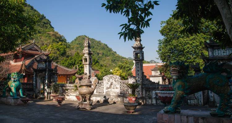 A scenic view of an ancient temple complex with lion statues and lush greenery.