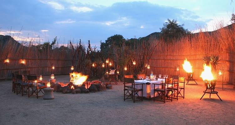 Outdoor dining setup with fire pit under a dusky sky.