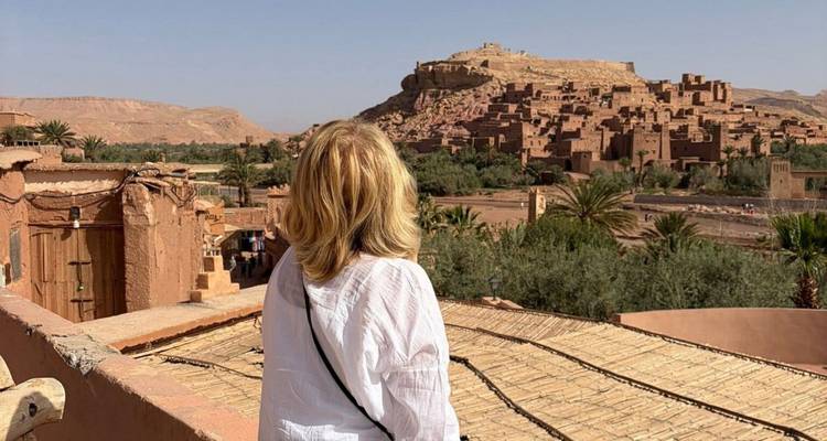 Una mujer mira hacia el ksar de tierra de Ait Benhaddou desde una terraza en la azotea.