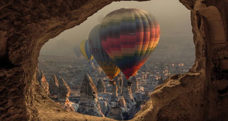 Montgolfières volant au-dessus de formations rocheuses au coucher du soleil.