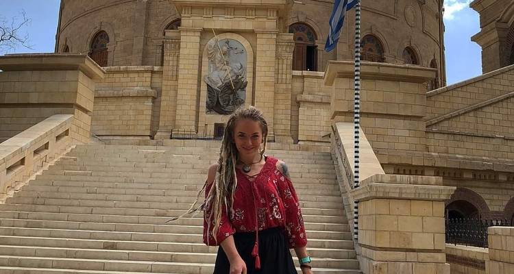 Frau steht auf Stufen vor einem großen religiösen Gebäude.