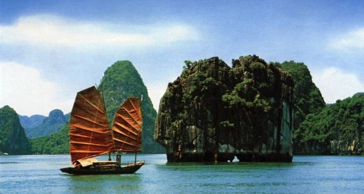Traditionele boot zeilt in Halong Bay met karstrotsen.