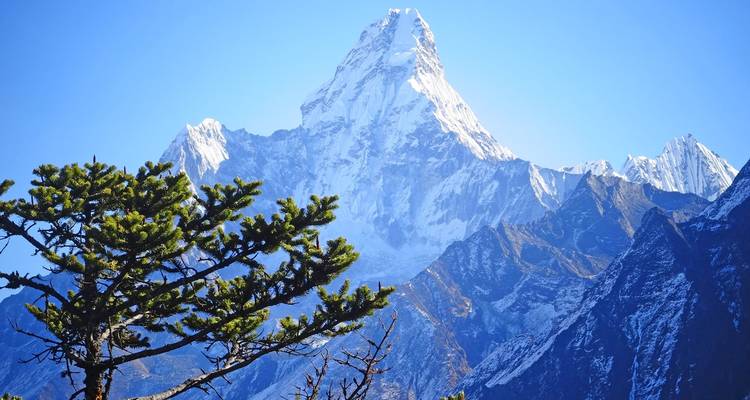 Nahaufnahme eines schneebedeckten Berggipfels mit blauem Himmel.