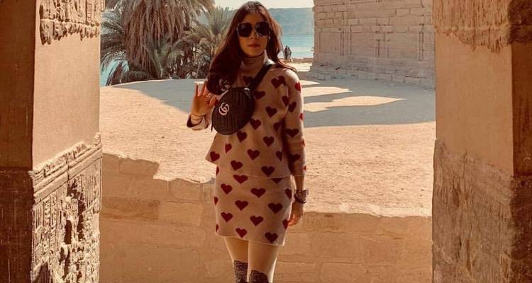 Eine Frau posiert neben einer Steinstruktur an einer historischen Stätte.