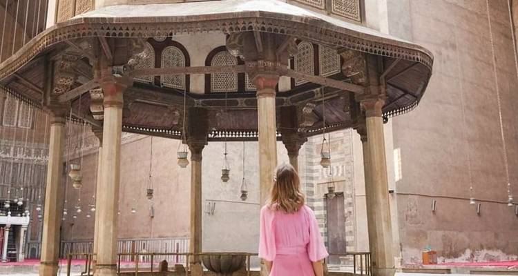 Frau, die an einer verzierten architektonischen Struktur steht.