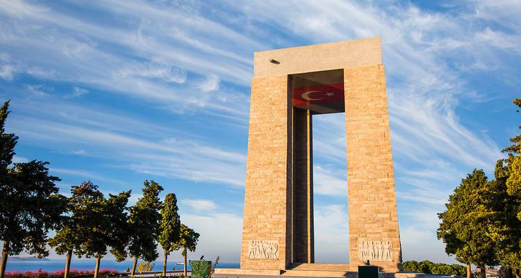Grand monument en pierre avec un drapeau turc sous un ciel dégagé.
