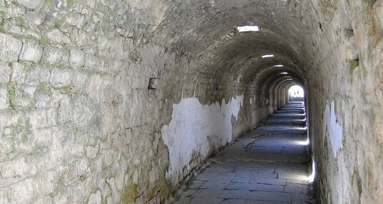 Tunnel de pierre avec une lumière au bout montrant une sortie.