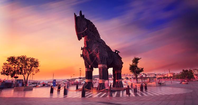 Grande statue de cheval en bois dressée contre un coucher de soleil dramatique.