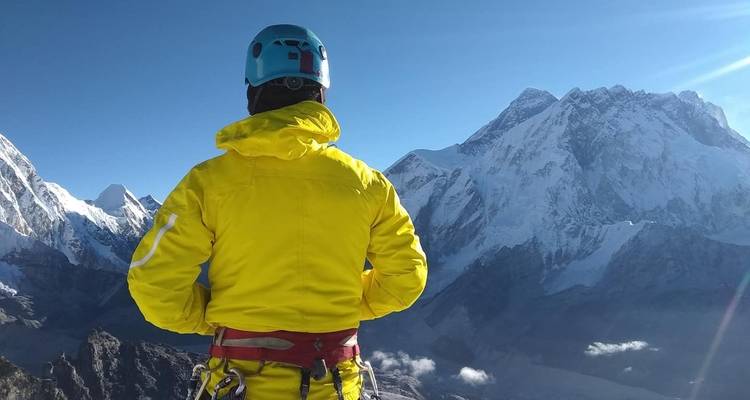 Person in hiking gear overlooking snowy mountains.