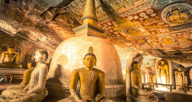 Intérieur d'un temple orné de statues dorées ornementées de Bouddha et de peintures murales.