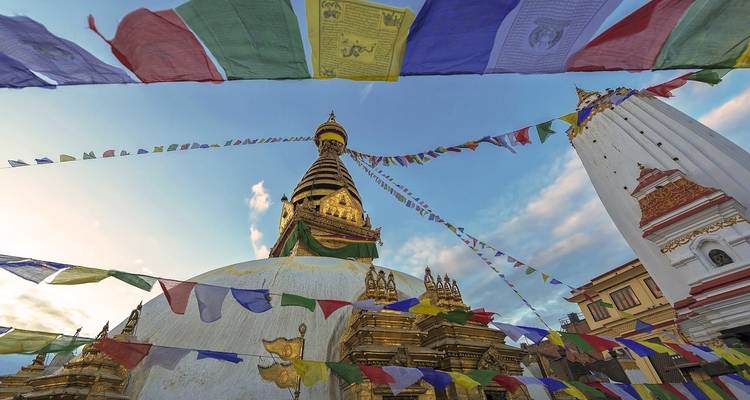 Colorful prayer flags above a stupa during evening.