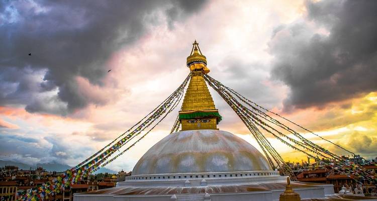 Golden stupa with a colorful sunset and prayer flags.