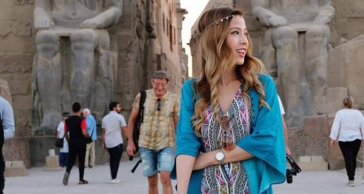 Femme posant devant des statues monumentales sur un site égyptien.