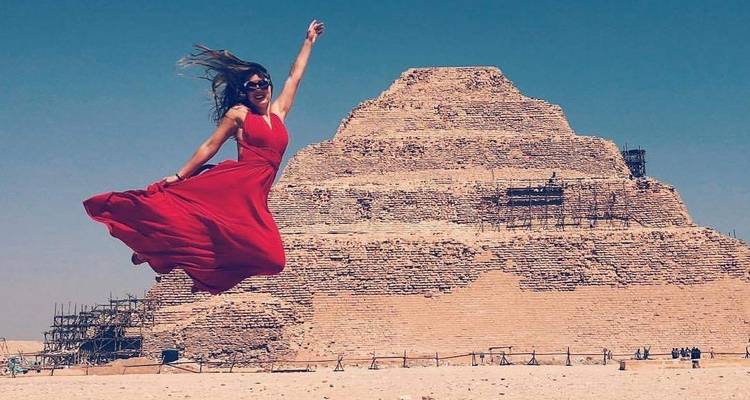 Femme sautant de joie devant la pyramide à degrés en Égypte.