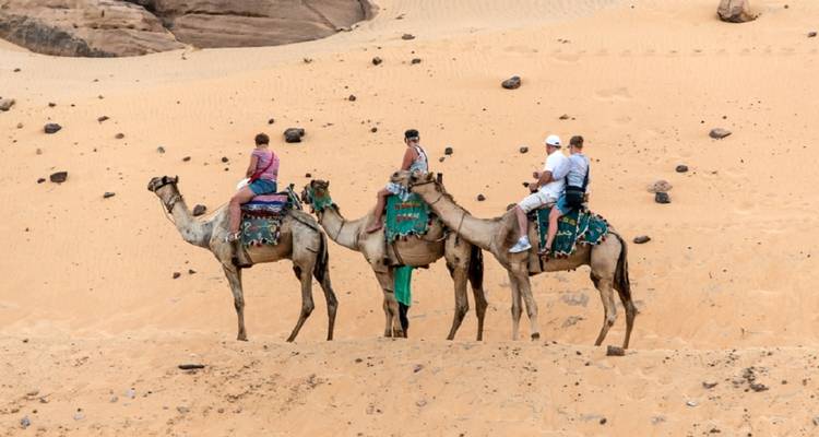 Viajeros montando camellos en un paisaje desértico