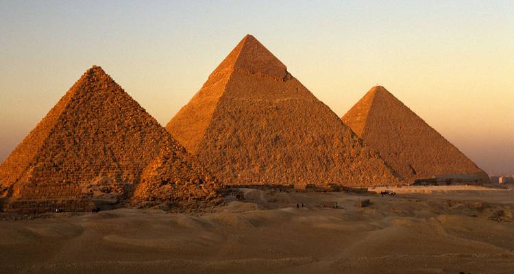 Las Pirámides de Giza bajo una puesta de sol dorada.