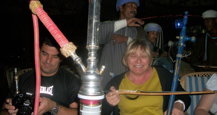 Personas disfrutando fumar hookah en un ambiente animado.