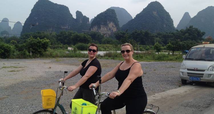 Deux femmes à vélo posant avec les montagnes karstiques de Yangshuo en arrière-plan