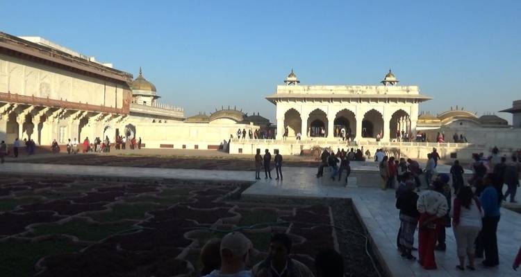 Group of tourists exploring a historical courtyard with gardens.