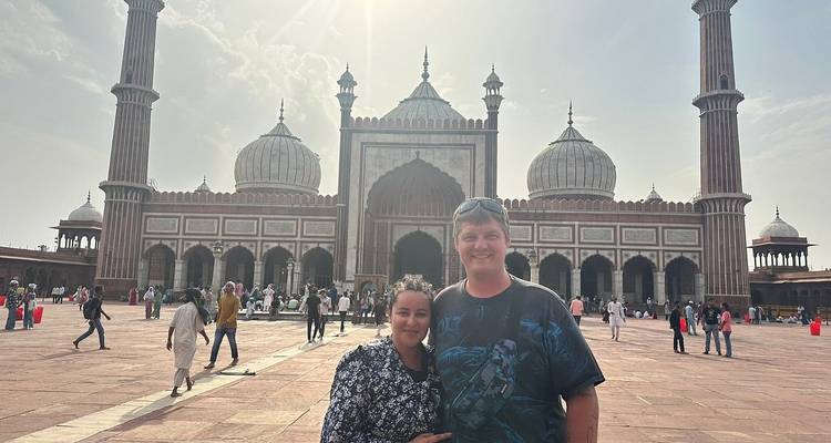 Couple posant devant une grande mosquée.