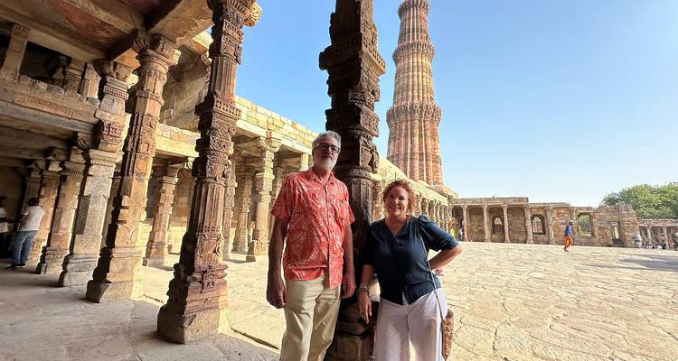 Couple posant devant une haute tour historique.