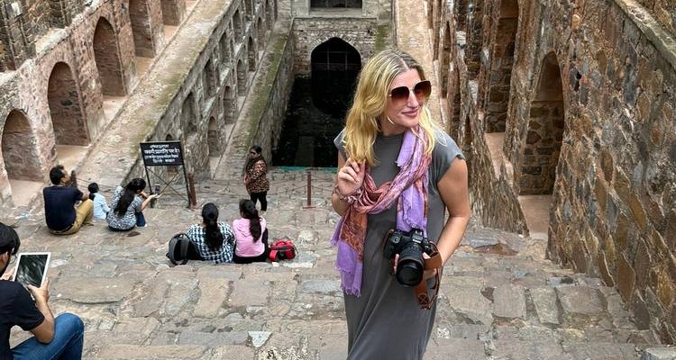 Femme posant devant un puits à degrés ancien.
