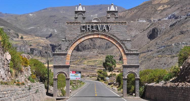 Arc avec le nom 'Chivay' au-dessus d'une route, entouré de montagnes.