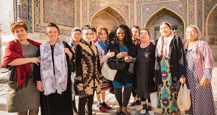 Groep vrouwen in kleurrijke kleding poserend voor een versierd gebouw.