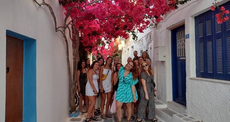 Groupe de personnes situées dans une ruelle étroite avec des fleurs éclatantes au-dessus.