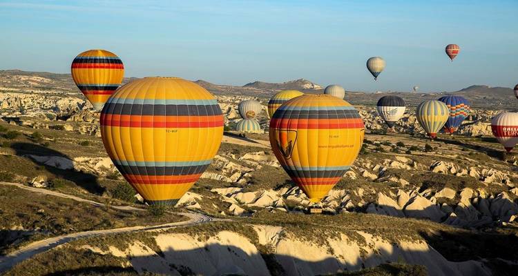 Globos aerostáticos ascendiendo sobre un paisaje rocoso.