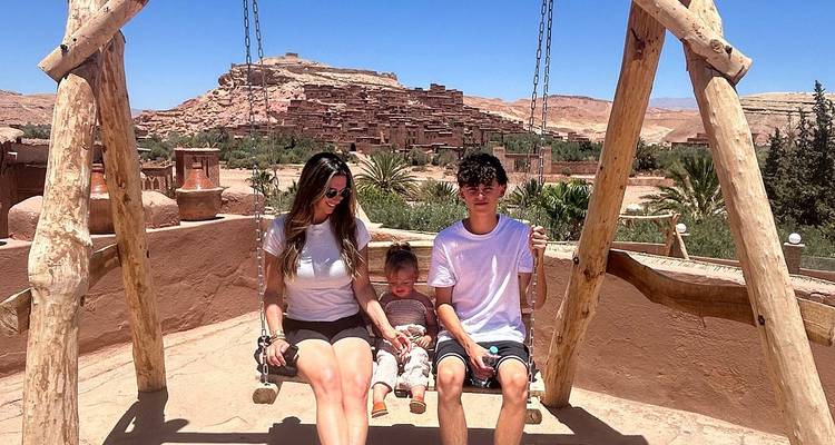 Familie mit Kindern auf einer Schaukel mit einer felsigen Landschaft im Hintergrund.