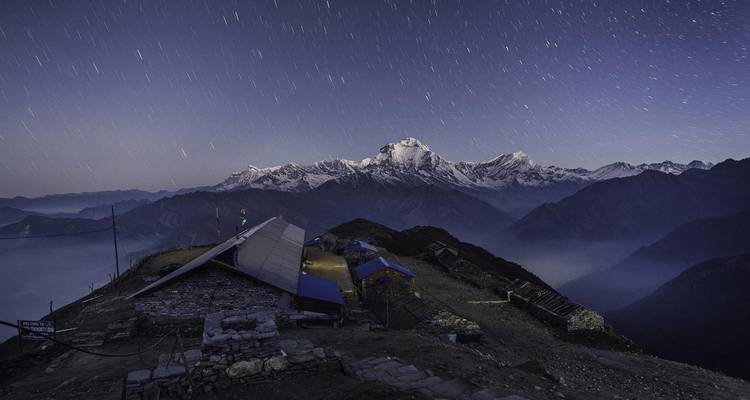 Nuit étoilée au-dessus de montagnes enneigées et d'un village.
